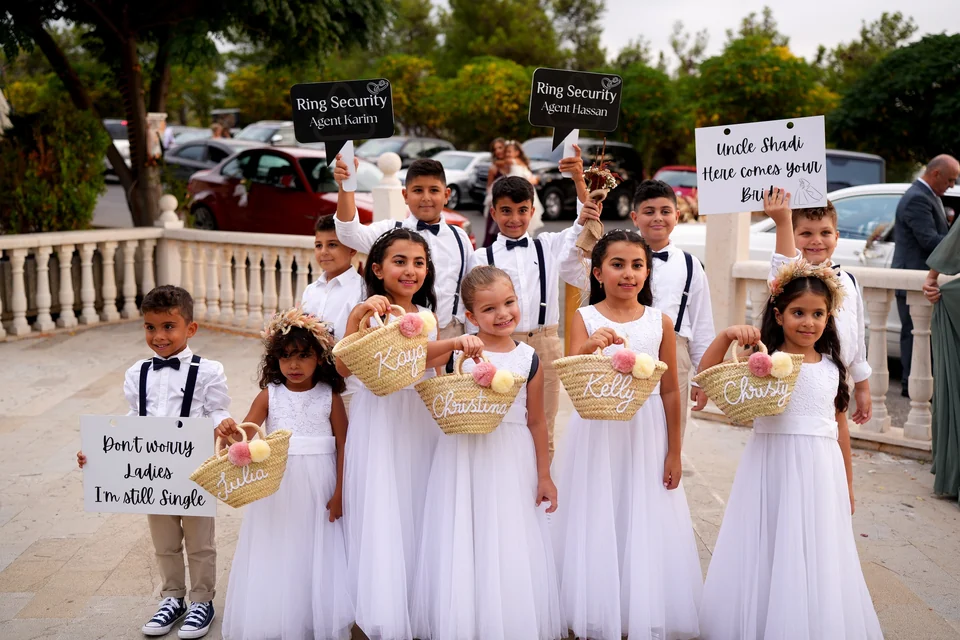 Page boys and flower girls holding personalised signs and named baskets