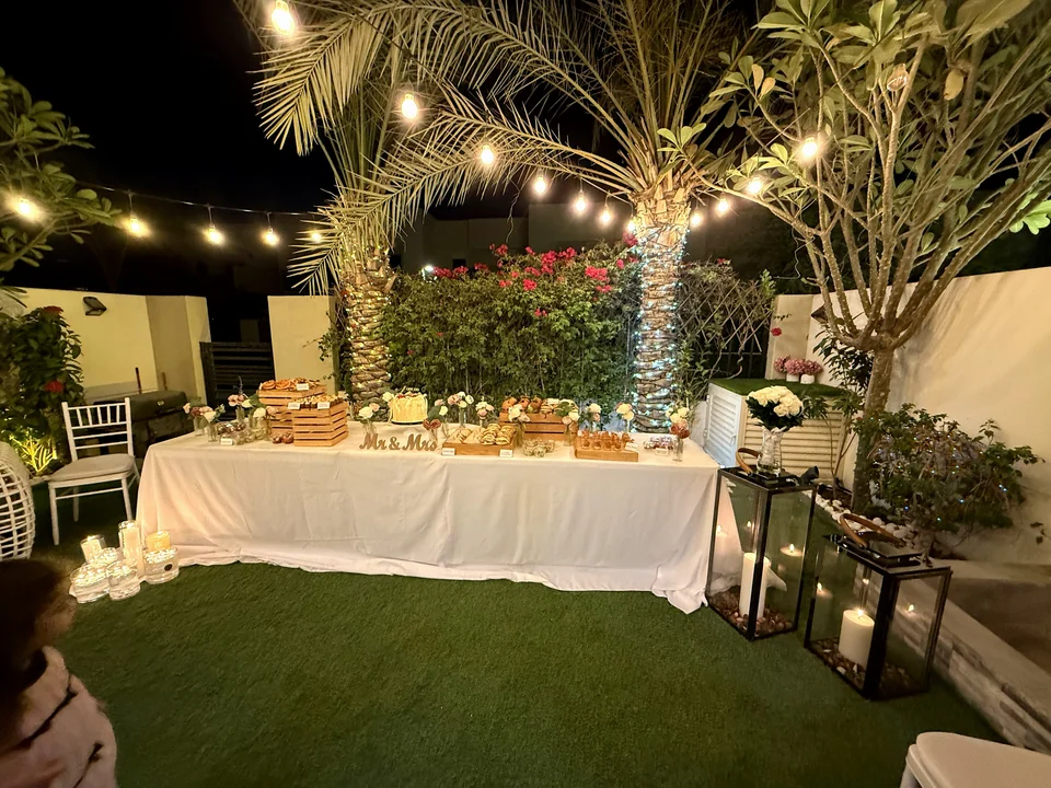Garden dessert table with wooden crates, fresh roses and a Mr and Mrs sign under string lights