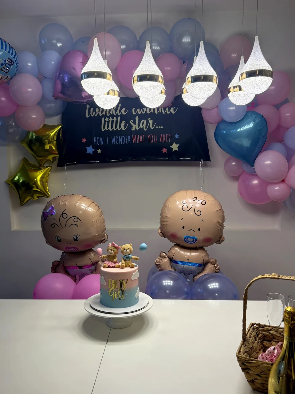 Gender reveal setup with a Twinkle Twinkle Little Star banner, pink and blue balloons and a small cake